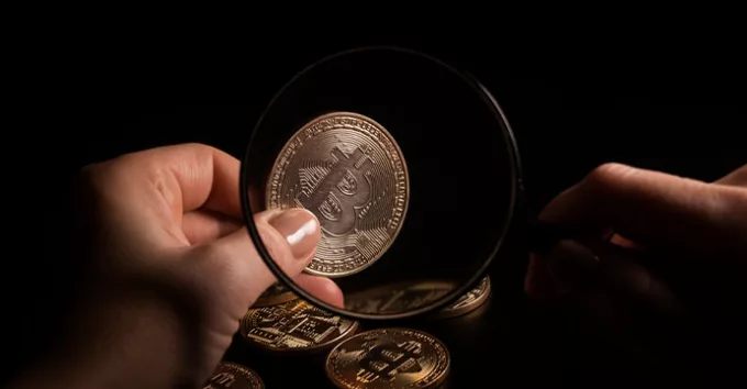 Person holding magnifying glass and looking through it on new digital asset