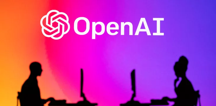 OpenAI logo with two people using laptop