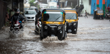 Commuter drive through a flooded street during heavy rains at Kurla