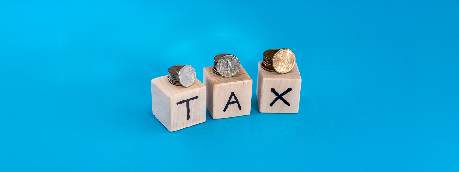 Coins with wooden cubes and text of tax