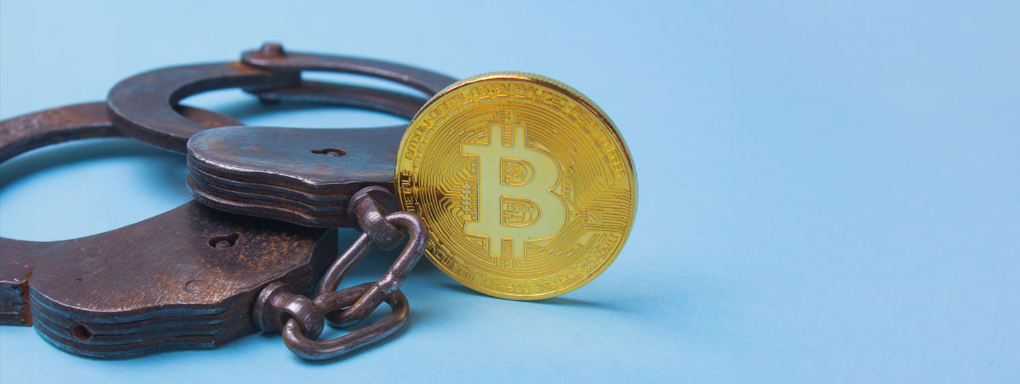 BTC coin and rusty handcuffs