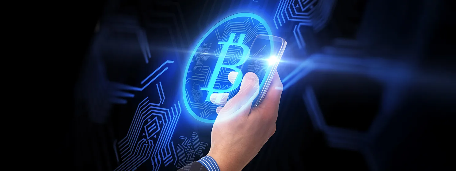 Close up of hand with smartphone and bitcoin