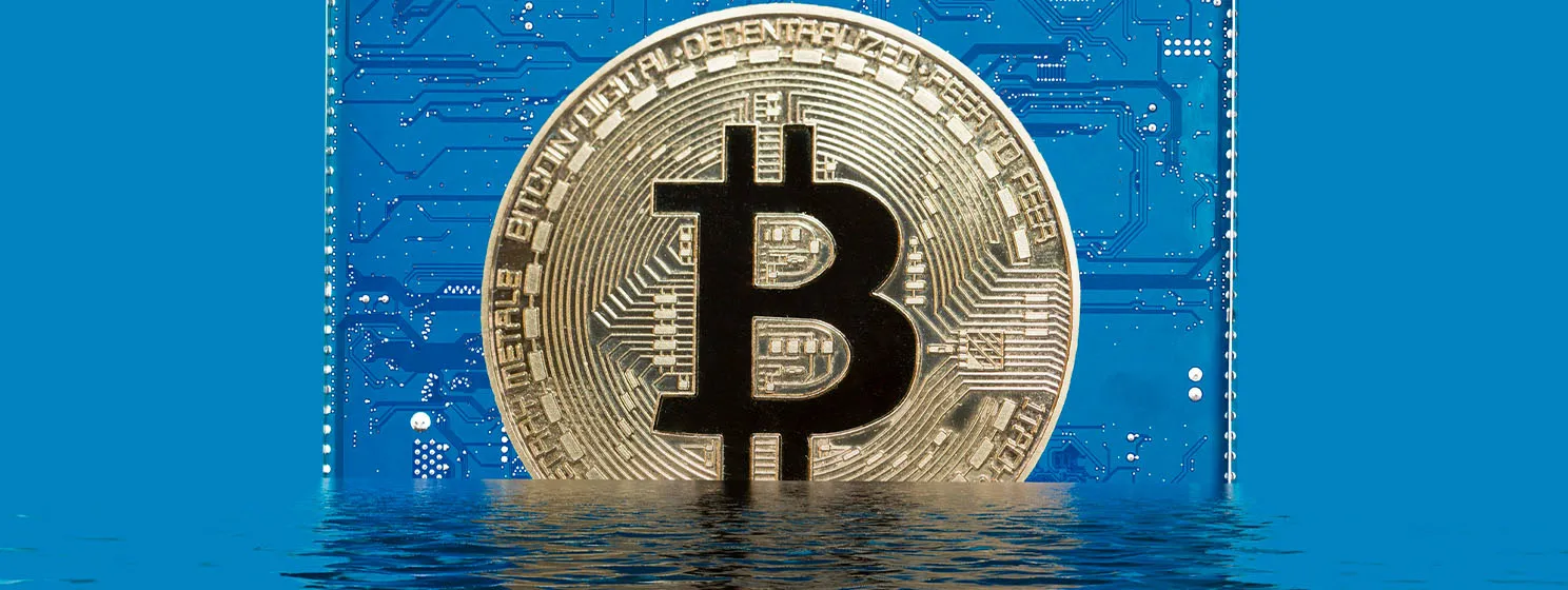 Bitcoin on a blue circuit board sinks into water