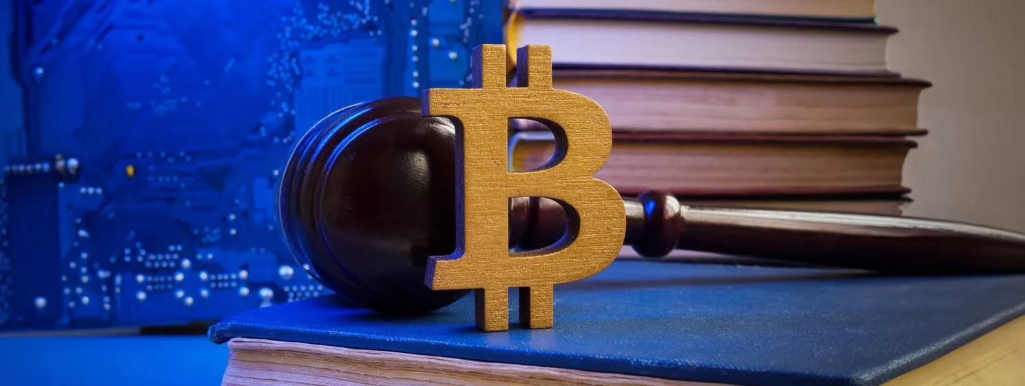 Wooden BTC logo over judge mallet, motherboard and books