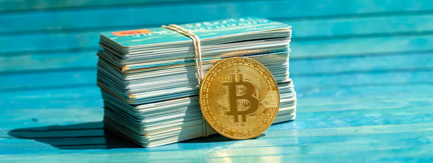 Gold bitcoin coin and a stack of old credit cards