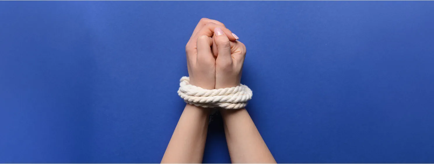 hands with tied around rope on color background