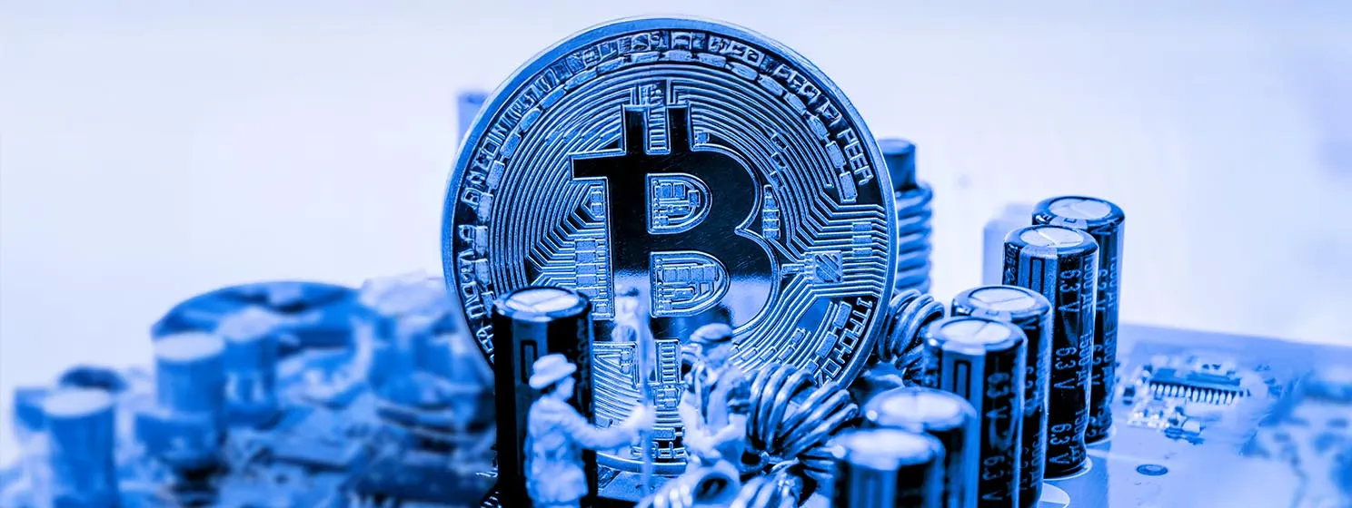 A Bitcoin coin on a computer motherboard with some small human figures symbolising mining.