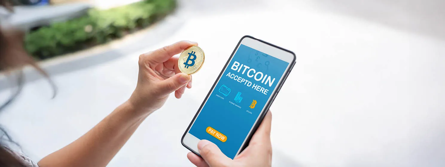 Hand holding gold bitcoin, paying online using a mobile app.