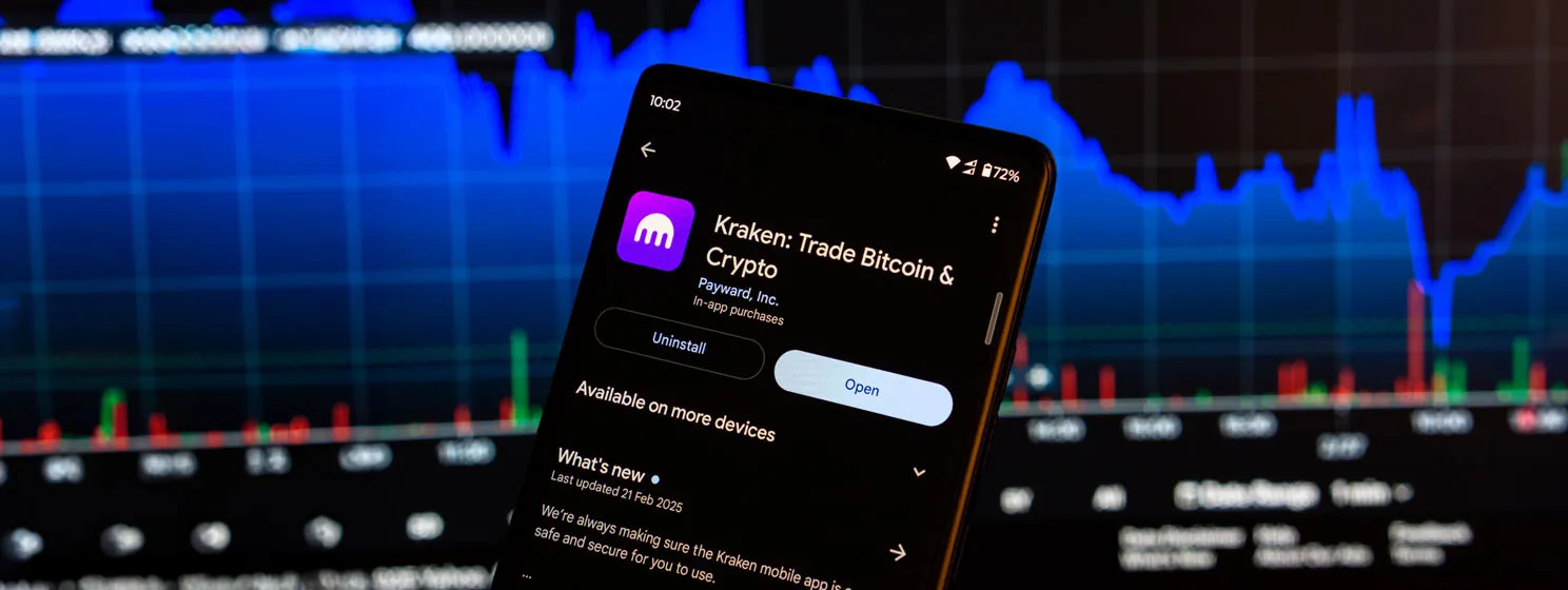 Kraken app installation screen on a smartphone and the financial market chart
