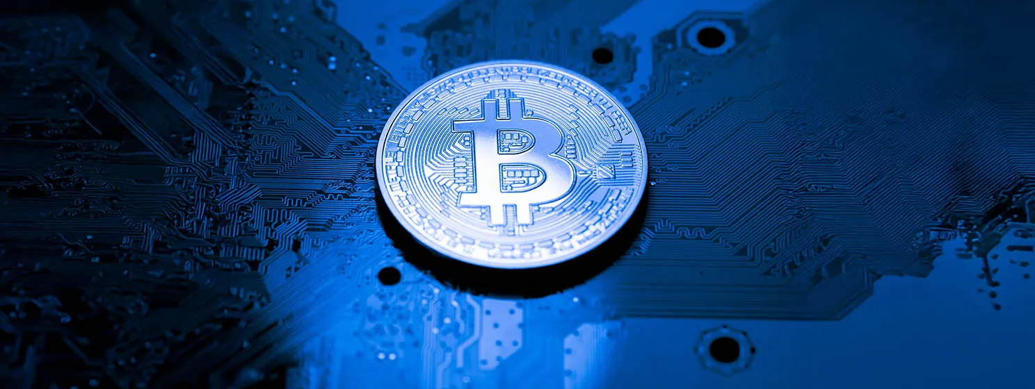 Close up of Bitcoin coin placed over a computer mother board.