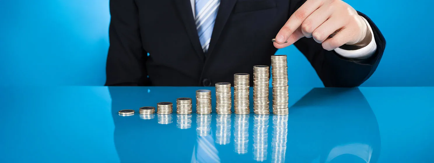 Businessman Stacking Coins At Desk.