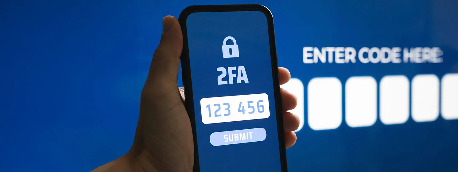 A hand holding a phone with a Two-factor Authentication 2FA Code Entry on screen.