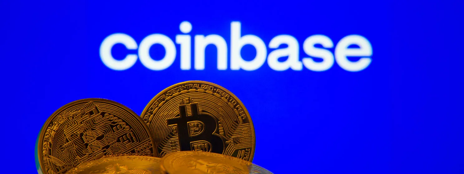 Bitcoin coins with the Coinbase logo on a screen in the background