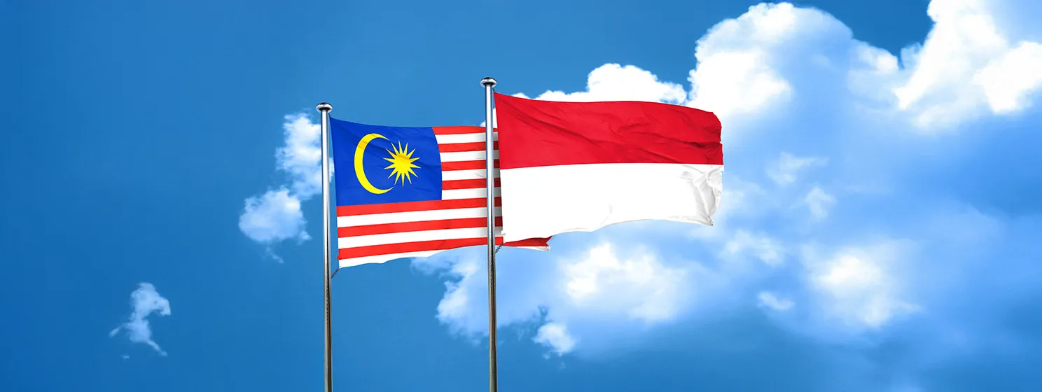 Malaysia flag with Indonesia flag waving in the wind against white cloudy blue sky together.