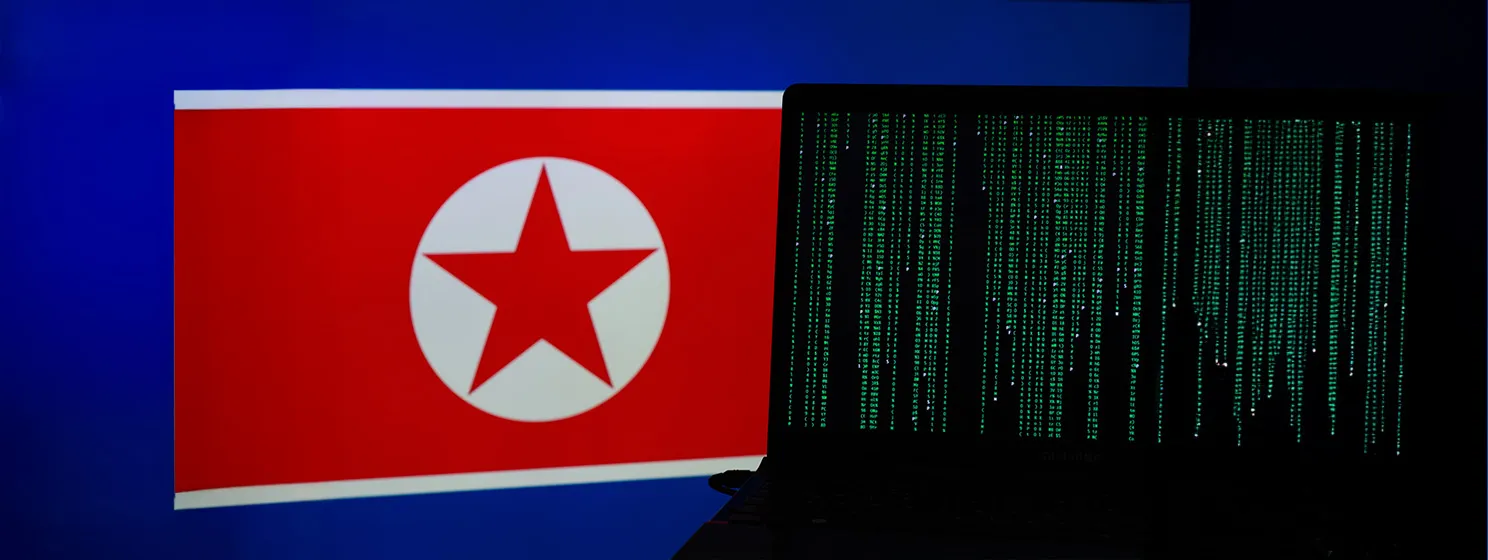 A laptop with green codes infront of a North Korean flag.