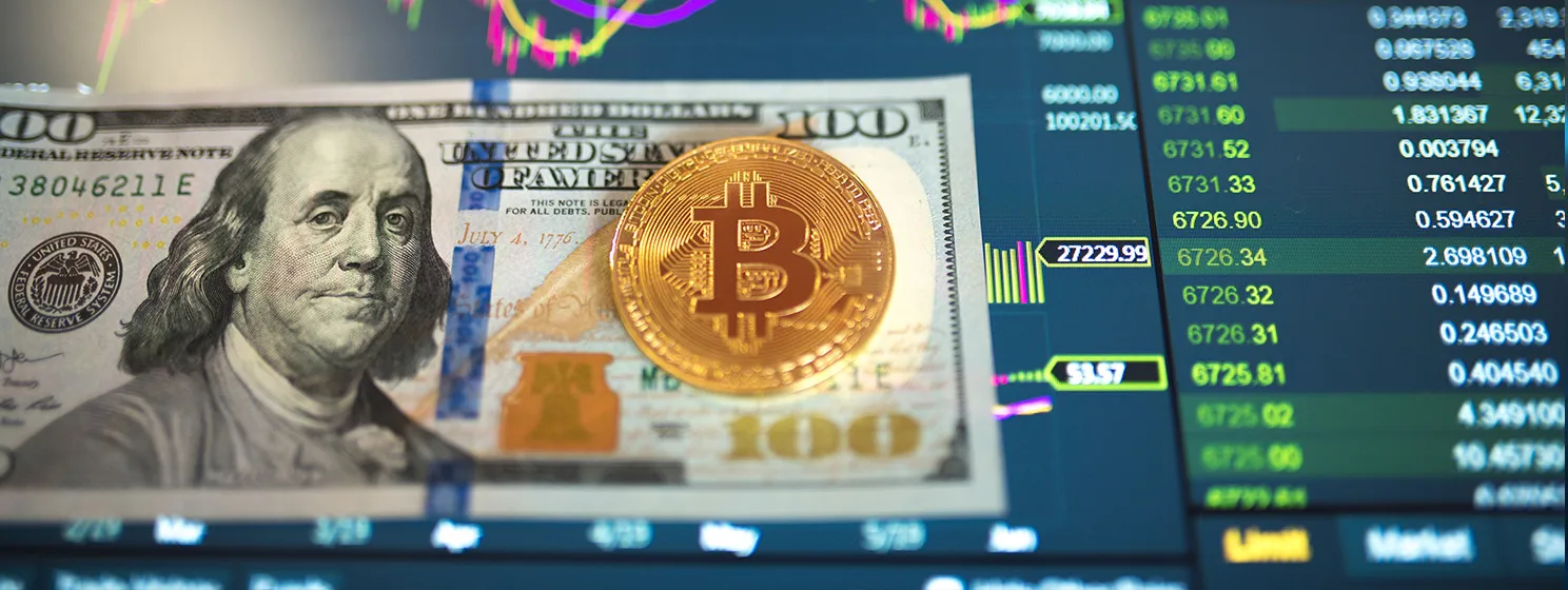 Paper bill Dollar, USD, blurred background. The electronic schedule of bitcoin on the exchange, volume trades, on the monitor lie gold coins bitcoin.