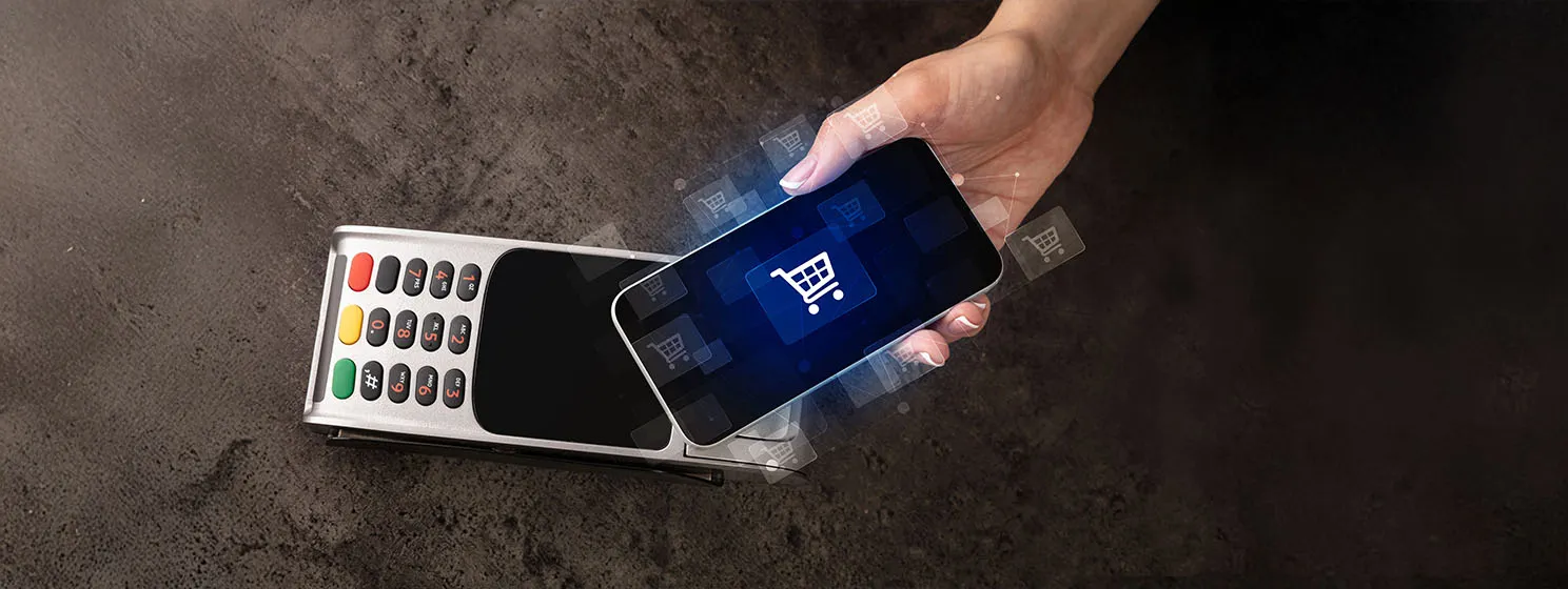 Shopping cart logo in the middle of a mobile phone with a hand holding it.
