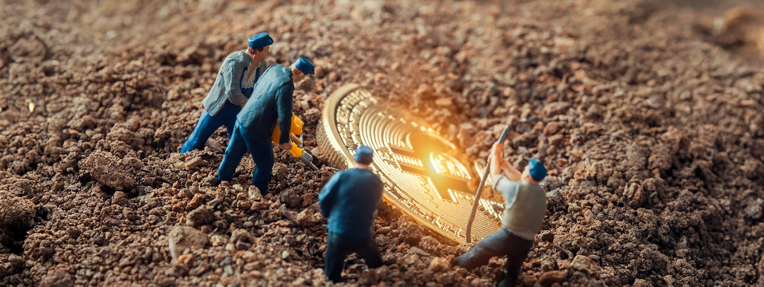 "Macro miner figurines digging ground to uncover big shiny bitcoin.