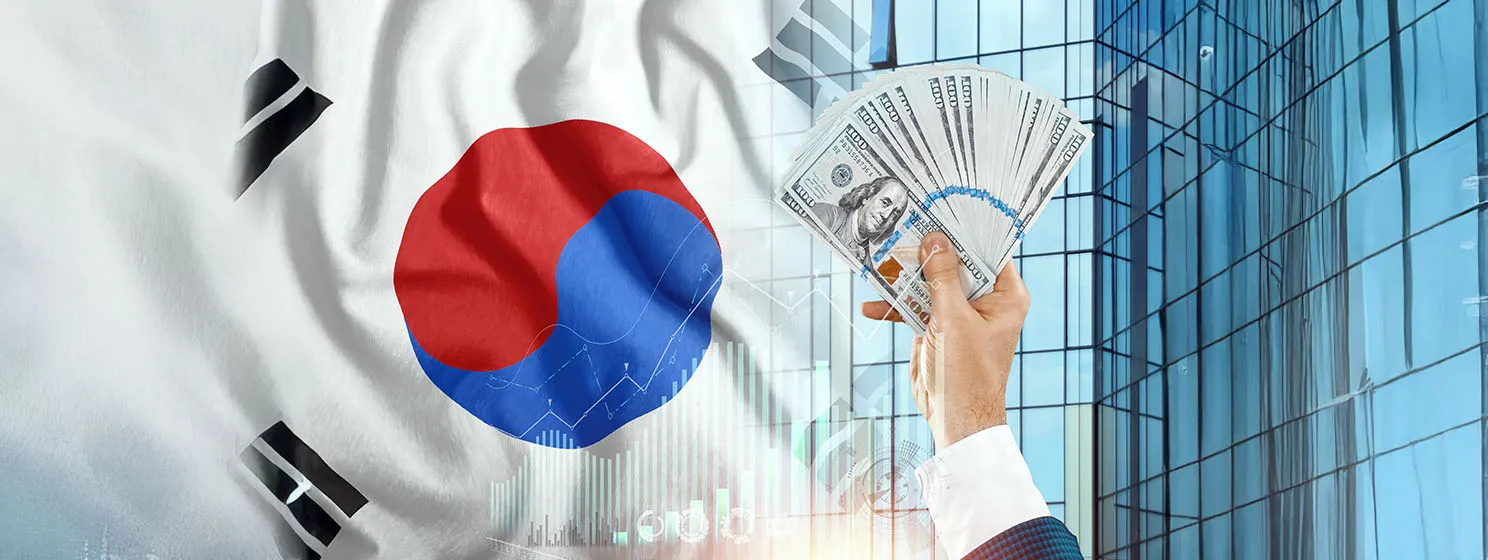 Money in a man's hand against the background of the flag of South Korea.