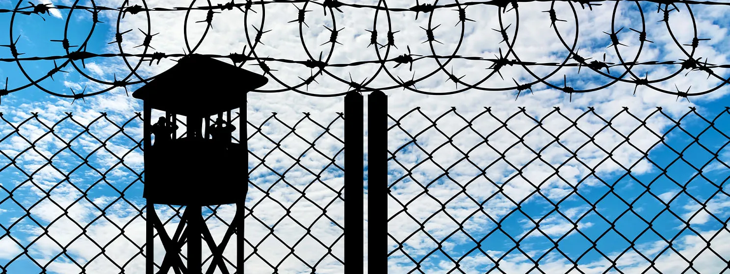 Silhouette of a watchtower and an iron fence