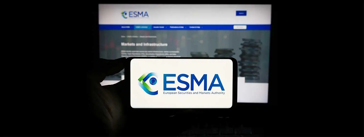 Person holding cellphone with logo of European Securities and Markets Authority (ESMA) in front of webpage