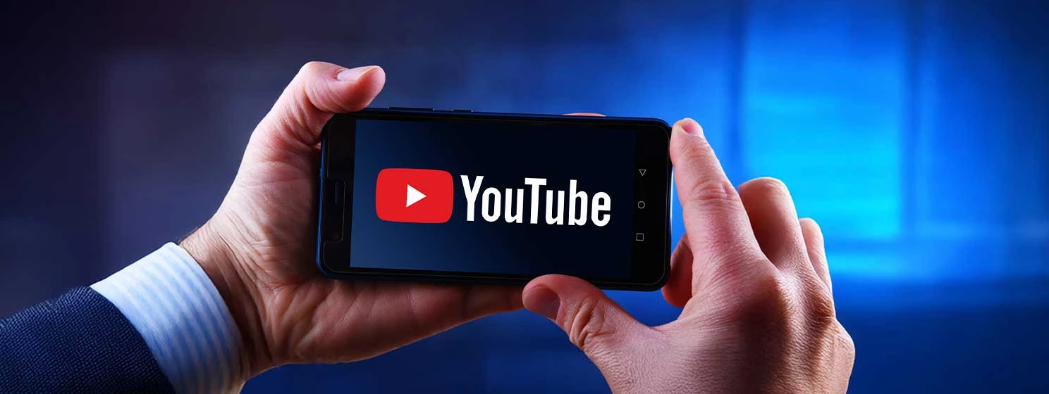 Hands holding smartphone displaying logo of YouTube