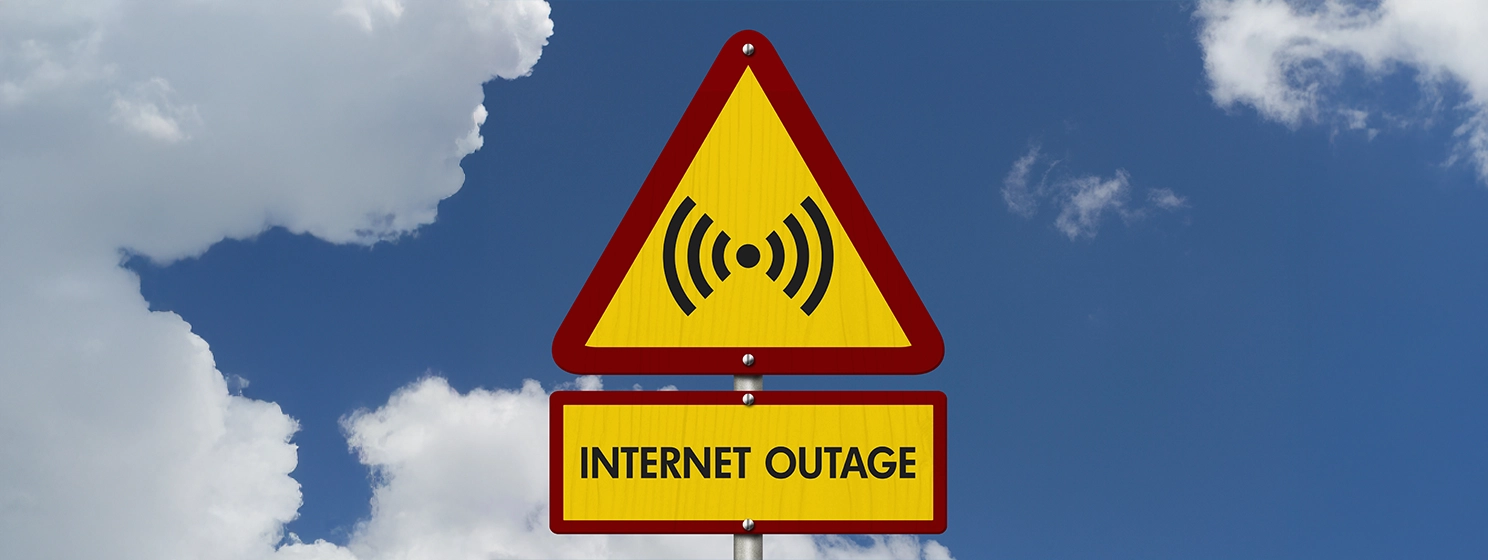 Internet Outage message on yellow warning road sign with sky.