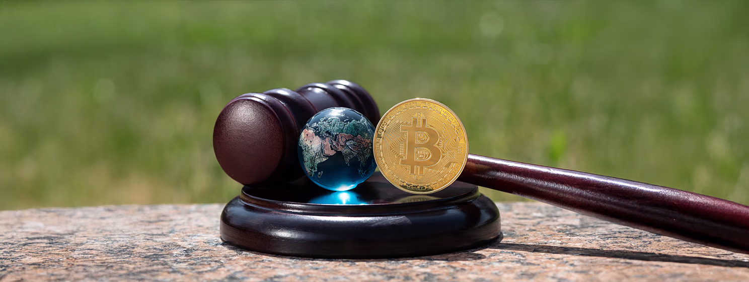 Judge's gavel, gold coin with bitcoin cryptocurrency symbol and glass symbolic globe.
