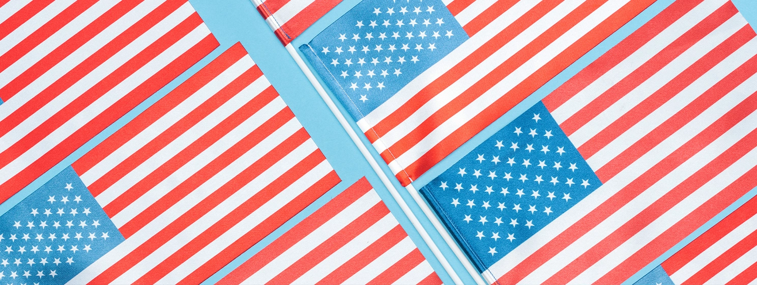 Flat lay with american flags on sticks on blue background, panoramic shot.