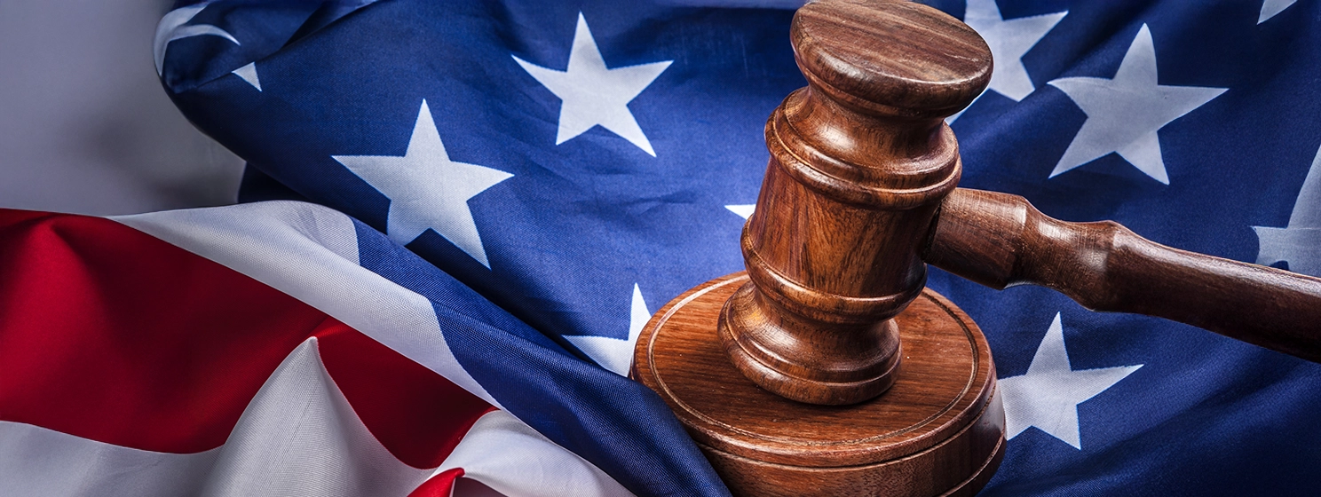 Wooden gavel and USA flag on table close up.